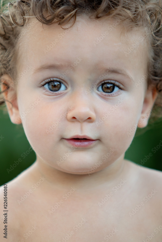 Beautiful baby with curly hair in the garden Beautiful baby with curly hair in the garden