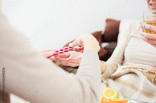 Close up photo of worried young daughter giving medications to her senior mother. Selective focus concept, focus on foreground. Healthcare and medicine concept. © Ivan