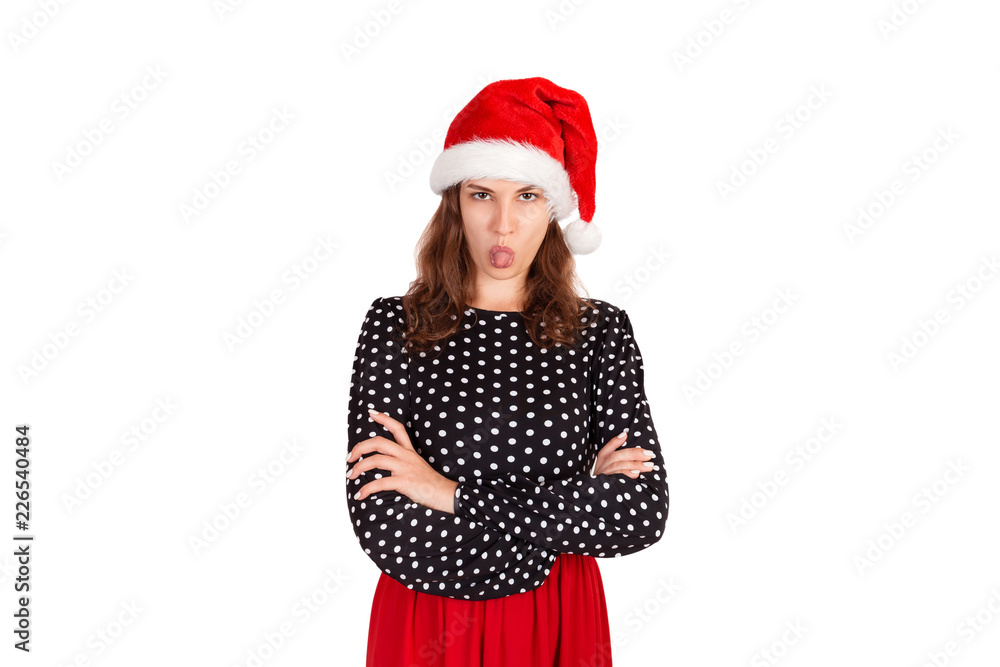 Dissatisfied brunette female model has disgusting expression, shows tongue, irritated with somebody. emotional girl in santa claus christmas hat isolated on white background. holiday concept Dissatisfied brunette female model has disgusting expression, shows tongue, irritated with somebody. emotional girl in santa claus christmas hat isolated on white background. holiday concept