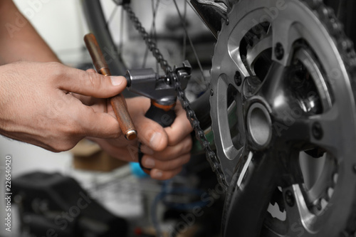 Professional mechanic repairing bicycle in modern workshop, closeup