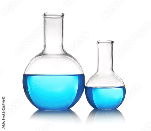Flasks with blue liquid on table against white background. Laboratory analysis