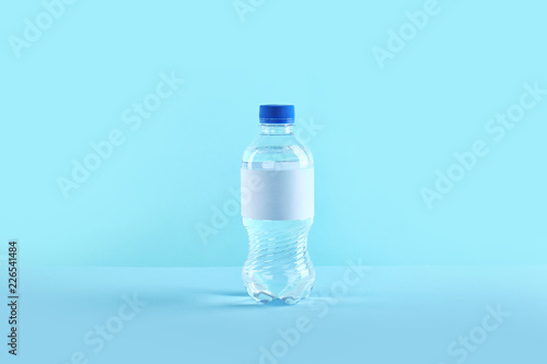 Plastic bottle of pure water with blank tag on color background
