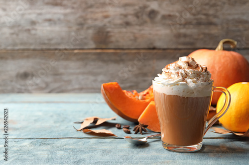 Fototapeta Naklejka Na Ścianę i Meble -  Glass cup with tasty pumpkin spice latte on wooden table. Space for text