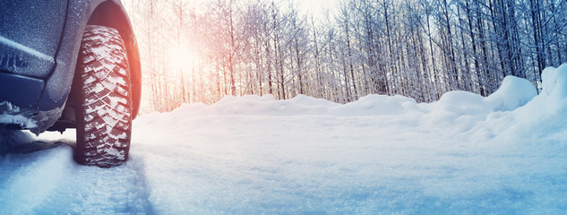 Car tires on winter road covered with snow. Snowy landscape with a vehicle