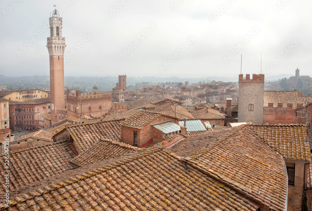 Morning cityscape of Siena with 14th century tower Torre del Mangia, Italy. Tuscany city roofs and old houses, UNESCO World Heritage Site
