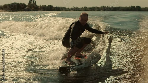 Man surfing on waves in slow motion. Wake surfing rider enjoy waves. Close up of extreme rider on wakesurf board photo