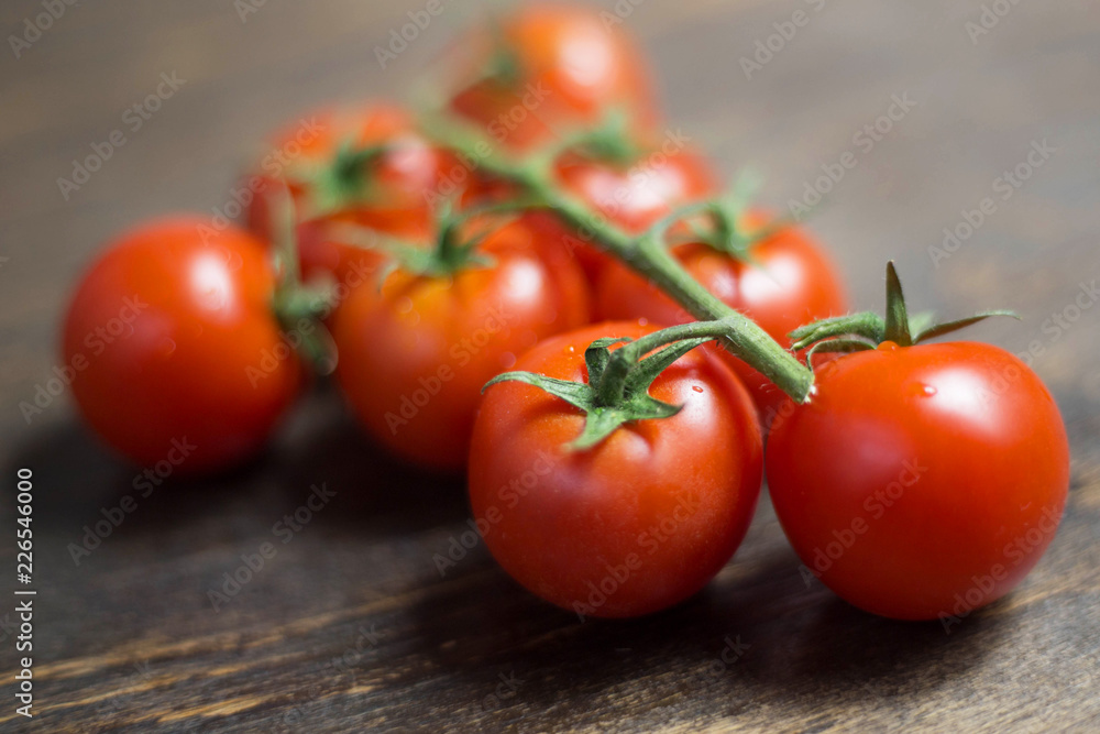 branch of red ripe fresh cherry tomatoes on a wooden board branch of red ripe fresh cherry tomatoes on a wooden board