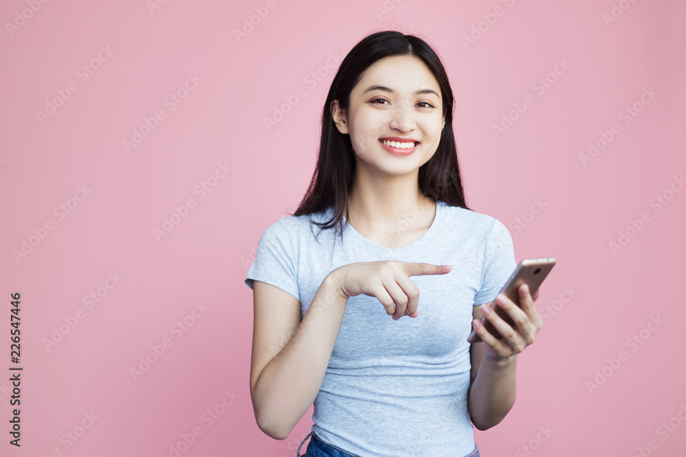A cheerful woman holds the phone close to her face, looks into the camera and laughs because she saw something funny, joyous, what she likes. She points her finger at the phone to share this news A cheerful woman holds the phone close to her face, looks into the camera and laughs because she saw something funny, joyous, what she likes. She points her finger at the phone to share this news