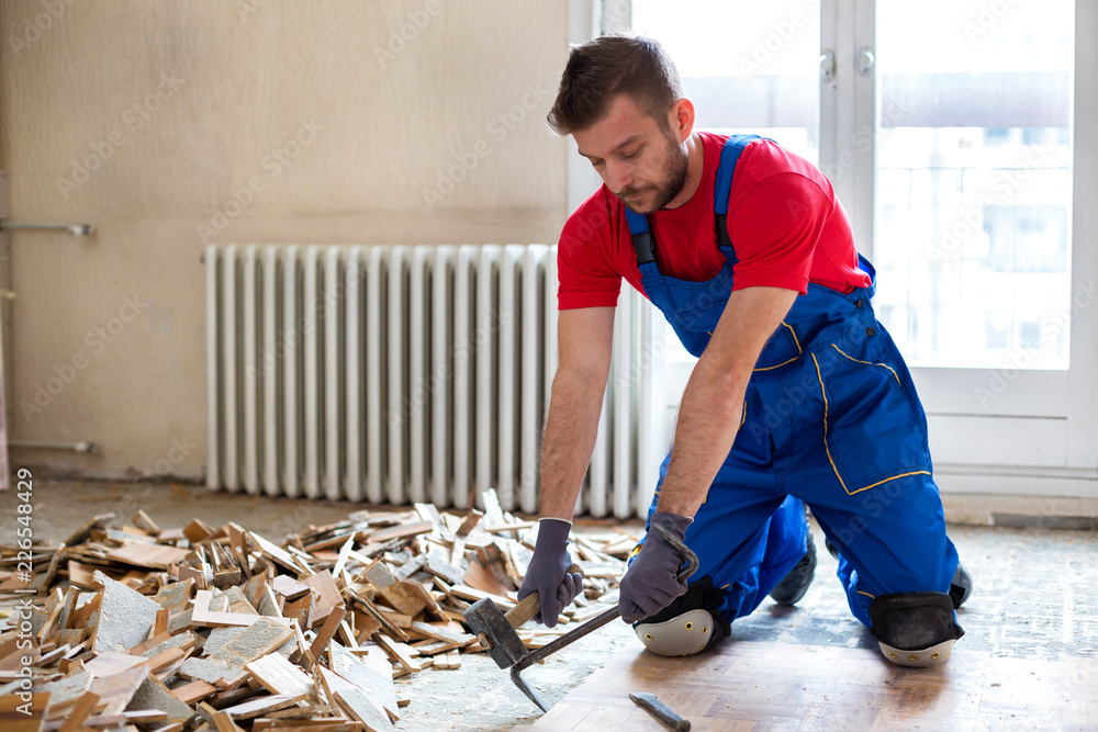 Handyman during work of removing old flooring - obrazy, fototapety, plakaty 