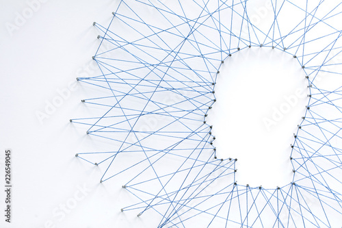 Human head shape made from a large grid of pins connected with string. Communication technology and mental health concept photo