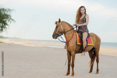 Pretty young lady riding a horse on the beach background of the sea