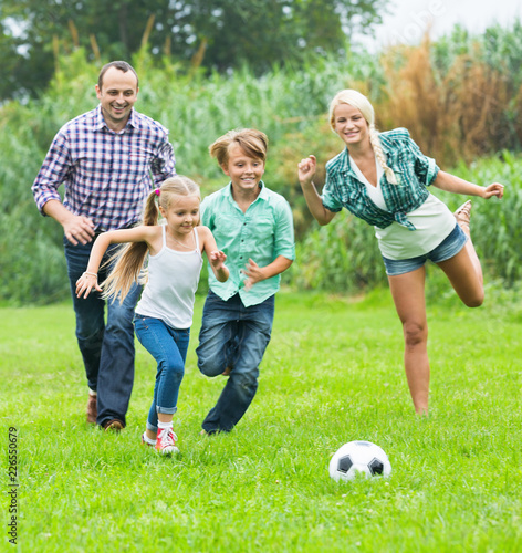Family of four playing football on field