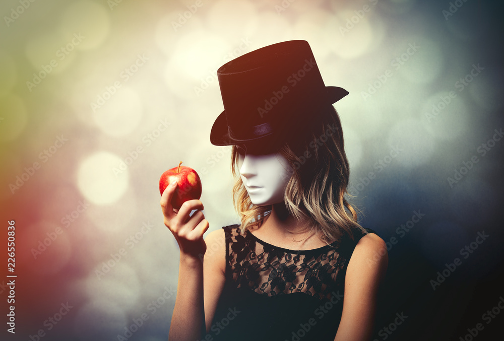 Portrait of a young style girl in top hat and white mask with apple on gray  background Stock Photo | Adobe Stock
