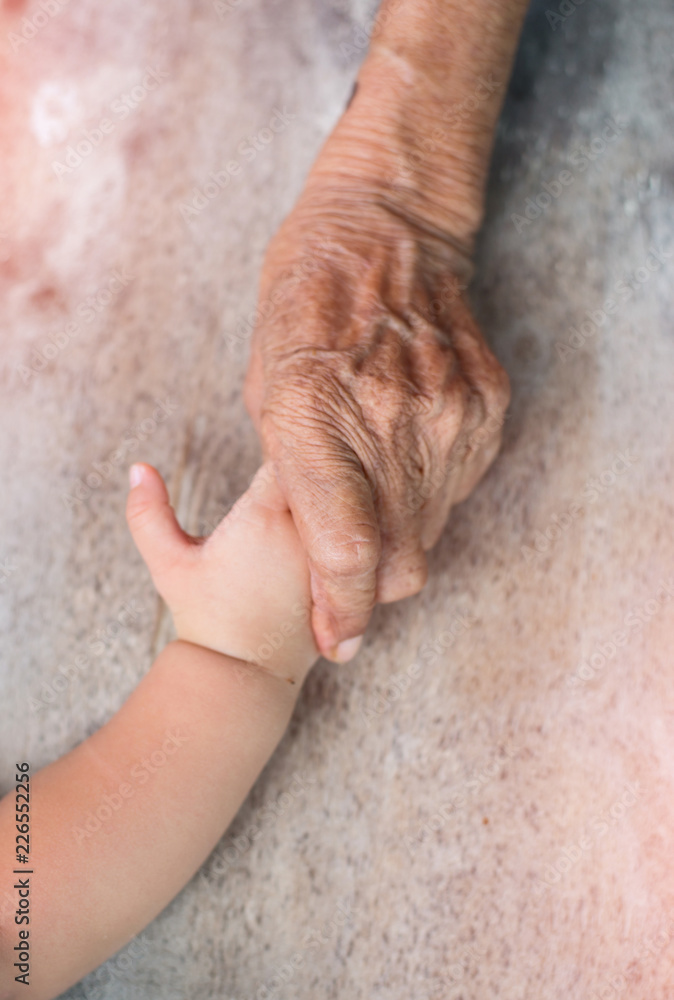 Naklejka premium Elderly hands are holding hands baby.