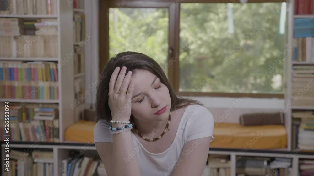 Depressed young woman suffering from headache feeling overworked and fatigue rubbing her temple at home Depressed young woman suffering from headache feeling overworked and fatigue rubbing her temple at home