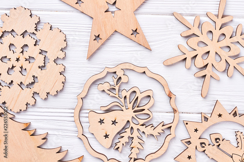 Close up carved wooden Christmas decorations. Cut out wooden figures for Christmas holidays on light wooden background close up. New Year handicraft ornaments.