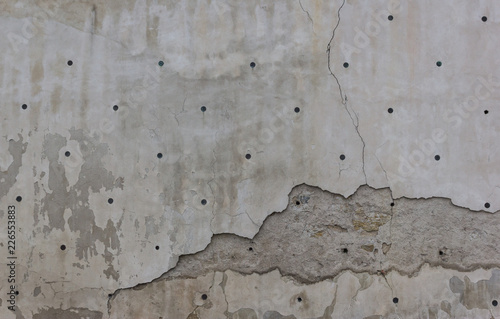 Old aged grey wall with cracks and black holes
