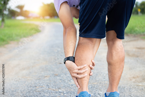 Male athlete runner muscle and ankle injury after jogging. Athlete man runner touching muscle in painful. Muscle and ankle injury concept.