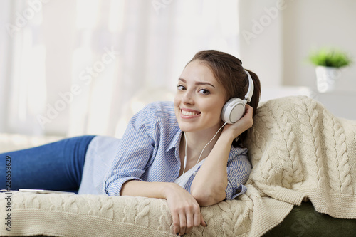 Girl in headphones smiling listening to music sitting in the room.