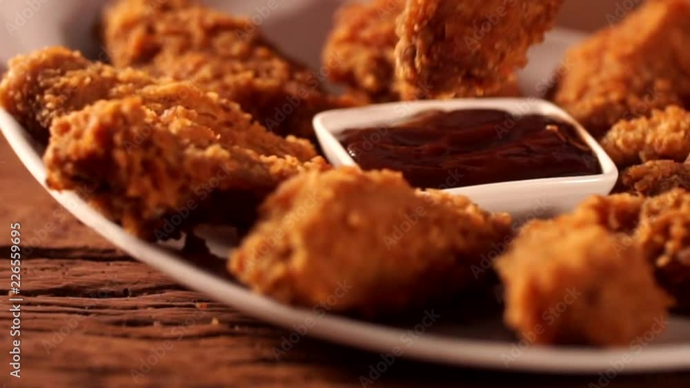 Hand put crispy fried chicken legs into barbecue sauce before eat. Hand put crispy fried chicken legs into barbecue sauce before eat.
