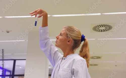 A young woman takes up her duties as  lab technitian. She wears a white smock to work with while analyzing. photo