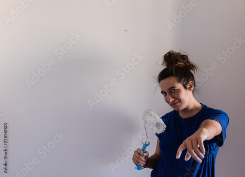 Smiling young girl painting a room with paint roller