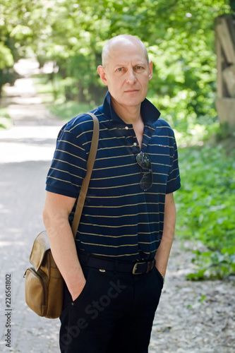 Fototapeta Naklejka Na Ścianę i Meble -  Middle-aged man walks in a summer park
