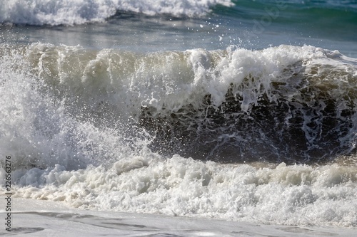 close up of a foamy wave crashing on to the shore