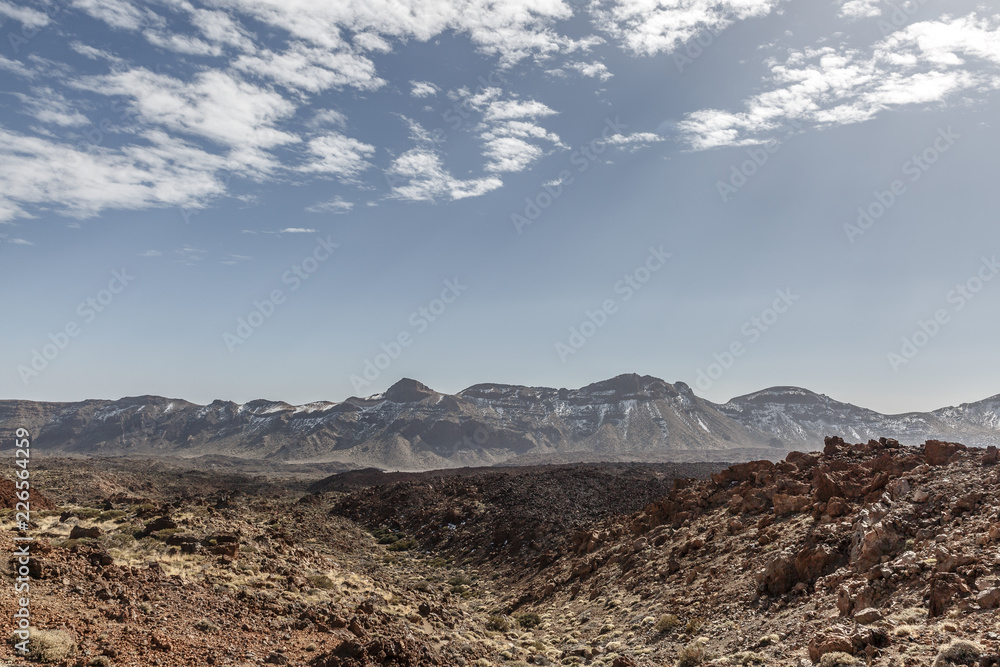 View of a desert landscape with a group of mountains in the background on a sunny day on the island of Tenerife