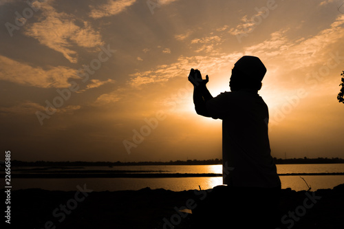 Silhouette Young asian muslim man praying on sunset,Ramadan festival concept