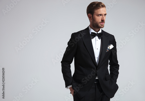 Photos serious  man wearing tuxedo and standing with hands in pockets