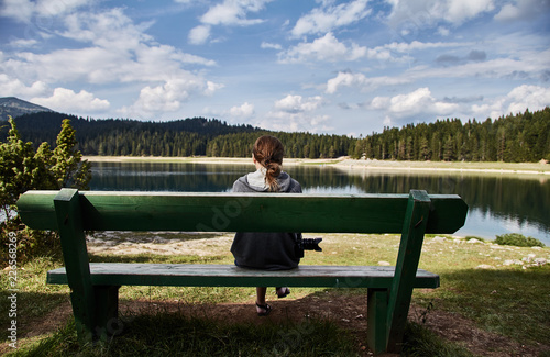 A young girl sitting on a bench. Black lake. Durmitor national Park. Montenegro. 