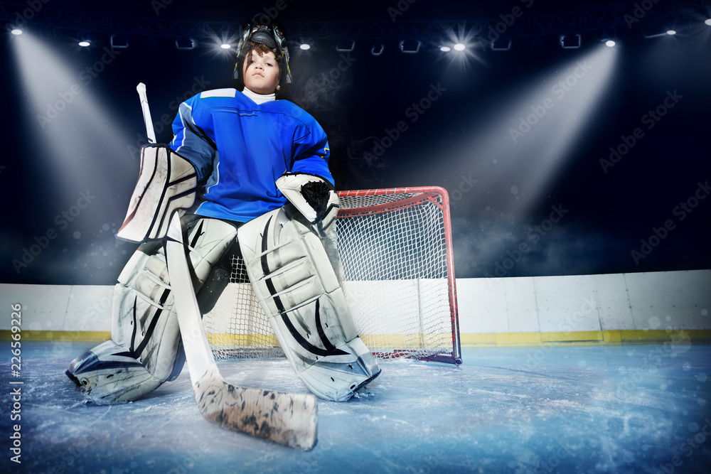 Fototapeta premium Young goalie in the spotlight of ice hockey arena