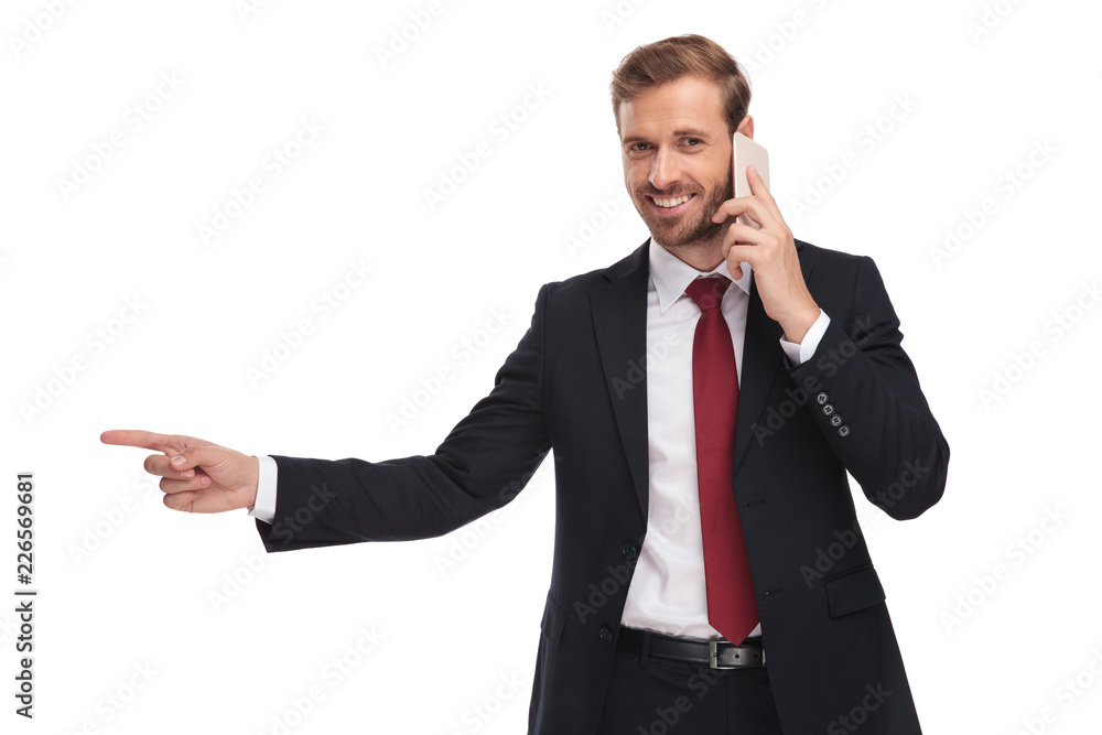 portrait of businessman talking on phone and pointing to side portrait of businessman talking on phone and pointing to side