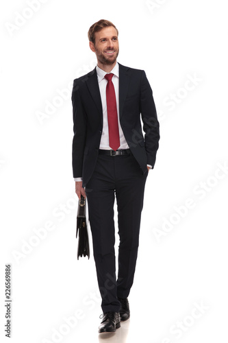 relaxed businessman with briefcase walking and looking up to side