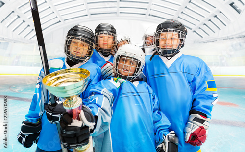 Happy hockey players with trophy on ice rink