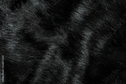 Highly detailed background texture of black fur made of synthetic animal long hair.