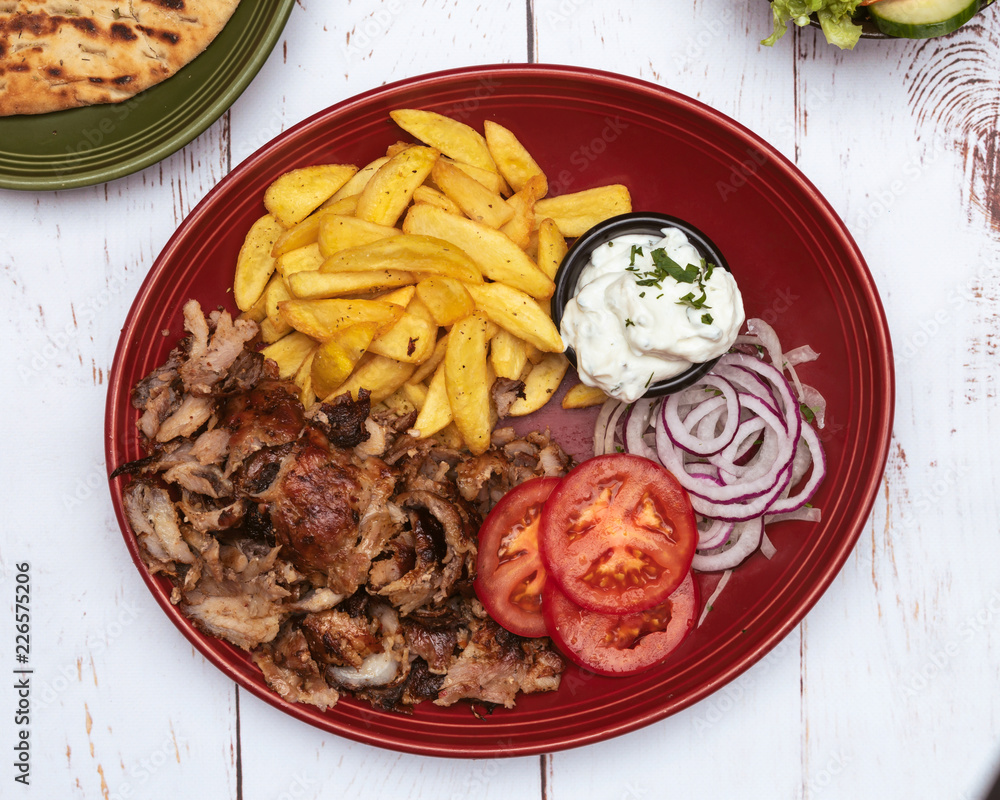 griechischer Gyros türkischer Döner Essen mit Pommes Tomaten und Zaziki top view macro auf einem weißem Holzbrett