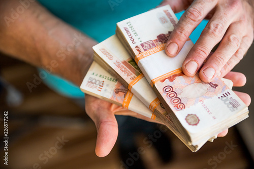 man giving money, Russian Ruble banknotes, over his desk in a dark office - bribery and corruption concept.russian rubles banknotes. Financial theme.stack of banknotes in a man's hand