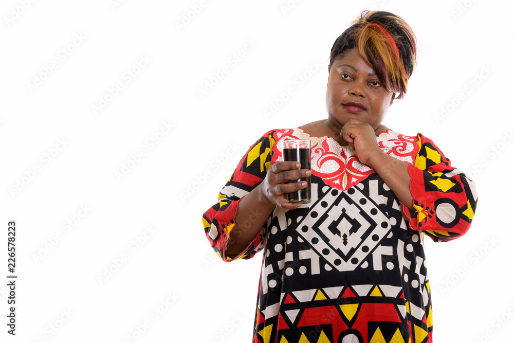 Studio shot of fat black African woman holding glass of soda dri Studio shot of fat black African woman holding glass of soda dri