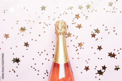Christmas or New Year pink background with  bottle of sparkling wine, rose champagne and gold decor, top view © 5ph