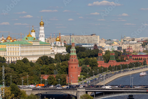 Moscow Kremlin with towers. Assumption Cathedral, in the Kremlin. Grand Kremlin Palace. The road near the Kremlin wall and the embankment near the river. Tourist ships sailing on the river.