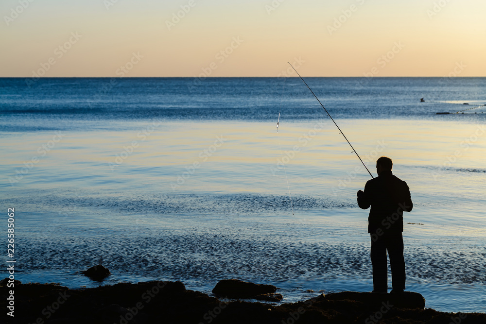 silhouette of a fisherman on the sea at sunset