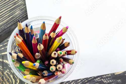 Color pencils in a glass on a sheet of white paper