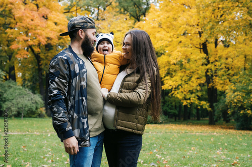 Happy family outdoors. Mother, father and baby on autumn walk in the park © photoguns