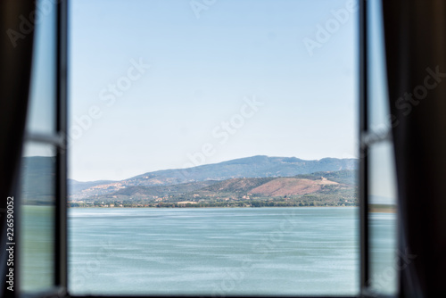 Fototapeta Jezioro Trazymeńskie w Castiglione del Lago, Umbria, Włochy Widok krajobrazu z otwartego okna w hotelu w słoneczny letni dzień, turkusowa woda