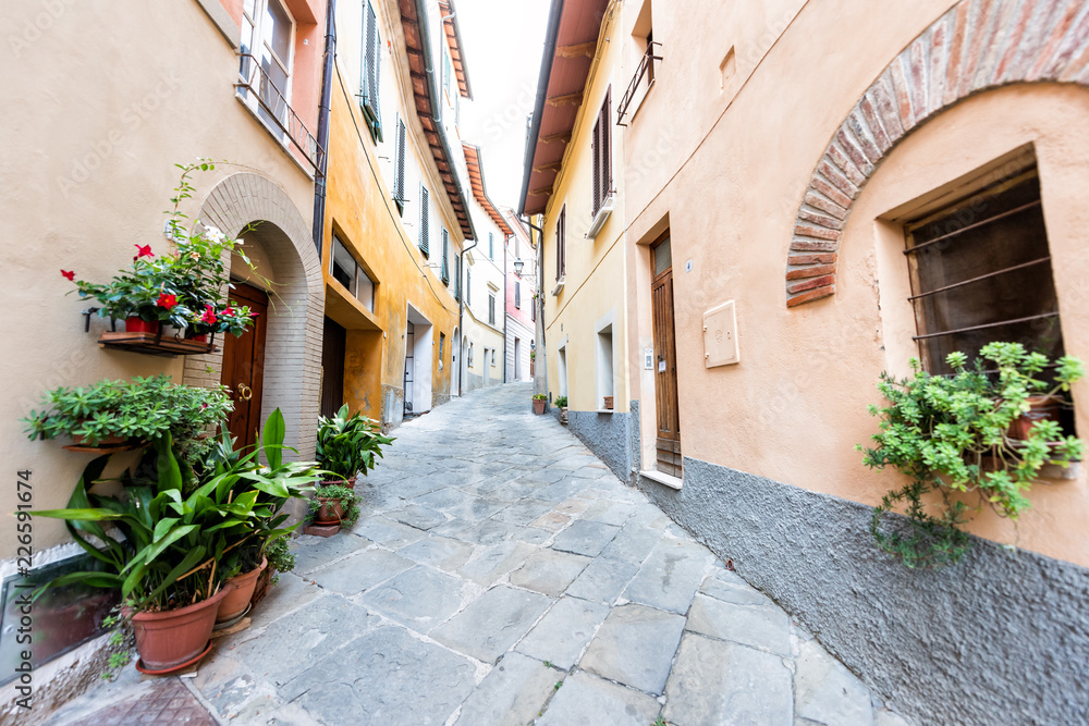 Chiusi, Italy street alley in small historic medieval town village in Umbria near Tuscany during sunny summer day, nobody, orange yellow bright vibrant colorful painted walls
