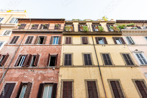 Rome, Italy street in historic center looking up at facade exterior windows wall during sunny summer day, nobody, orange yellow red old colorful painted walls