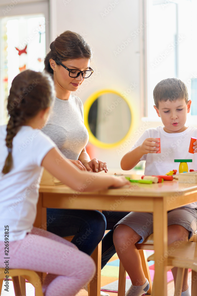 Preschool Teacher With Children Playing With Colorful Wooden Didactic