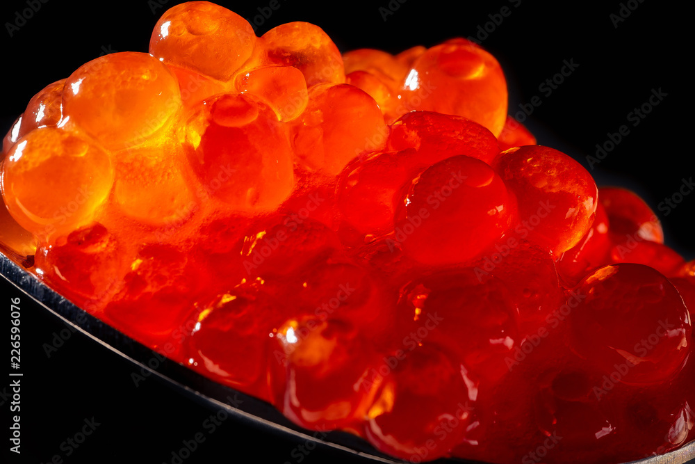 Red caviar in spoon on black background, macro photo Red caviar in spoon on black background, macro photo